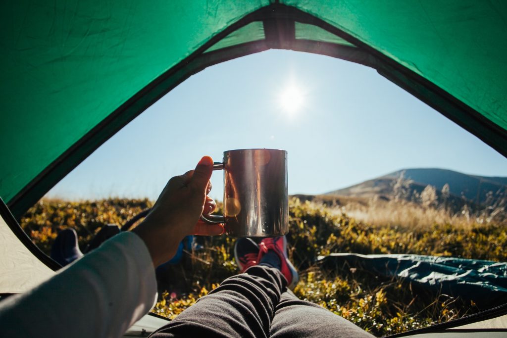Aufwachen und Kaffee trinken im Zelt. Übernachten im Freien als Mikroabenteuer. 